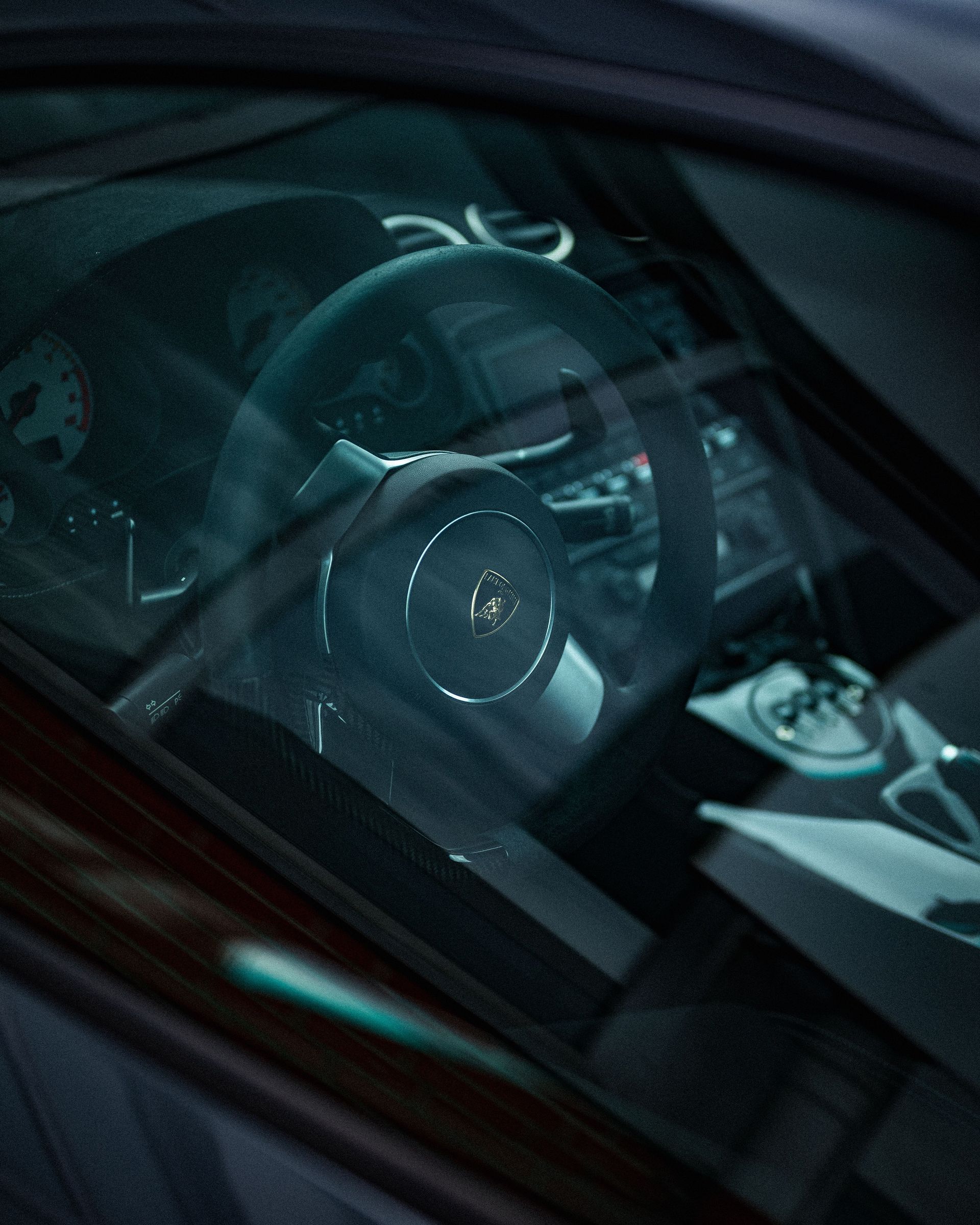 Close-up view of Lamborghini Gallardo interior featuring iconic steering wheel and dashboard details.