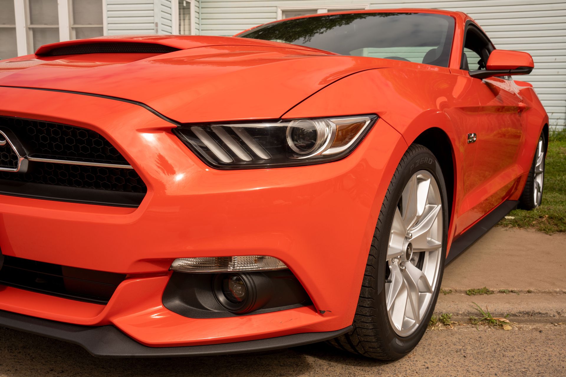 Front view of a bright orange sports car parked on an urban street, showcasing sleek design.