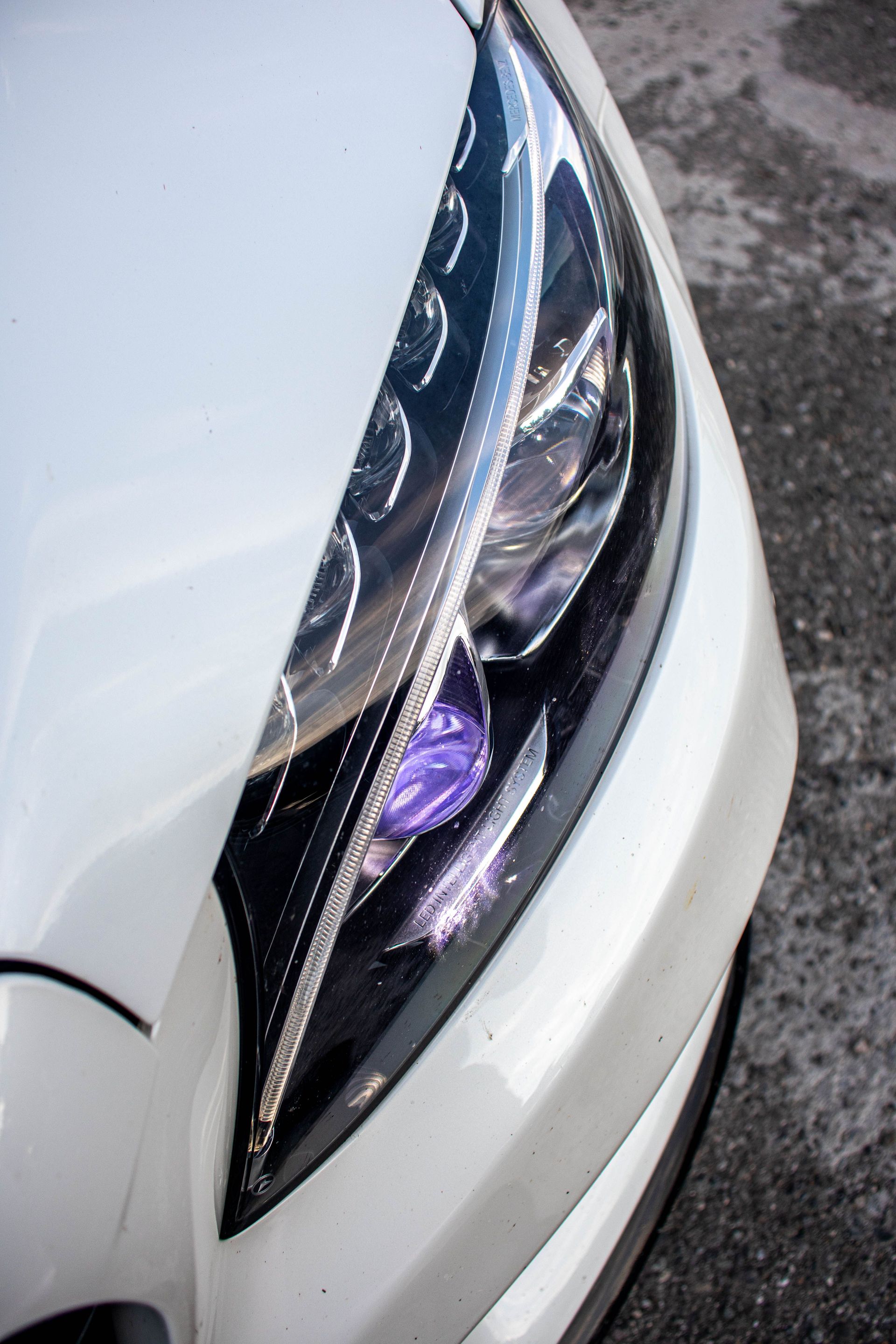 Detailed shot of a sleek luxury car headlight, showcasing design and elegance.